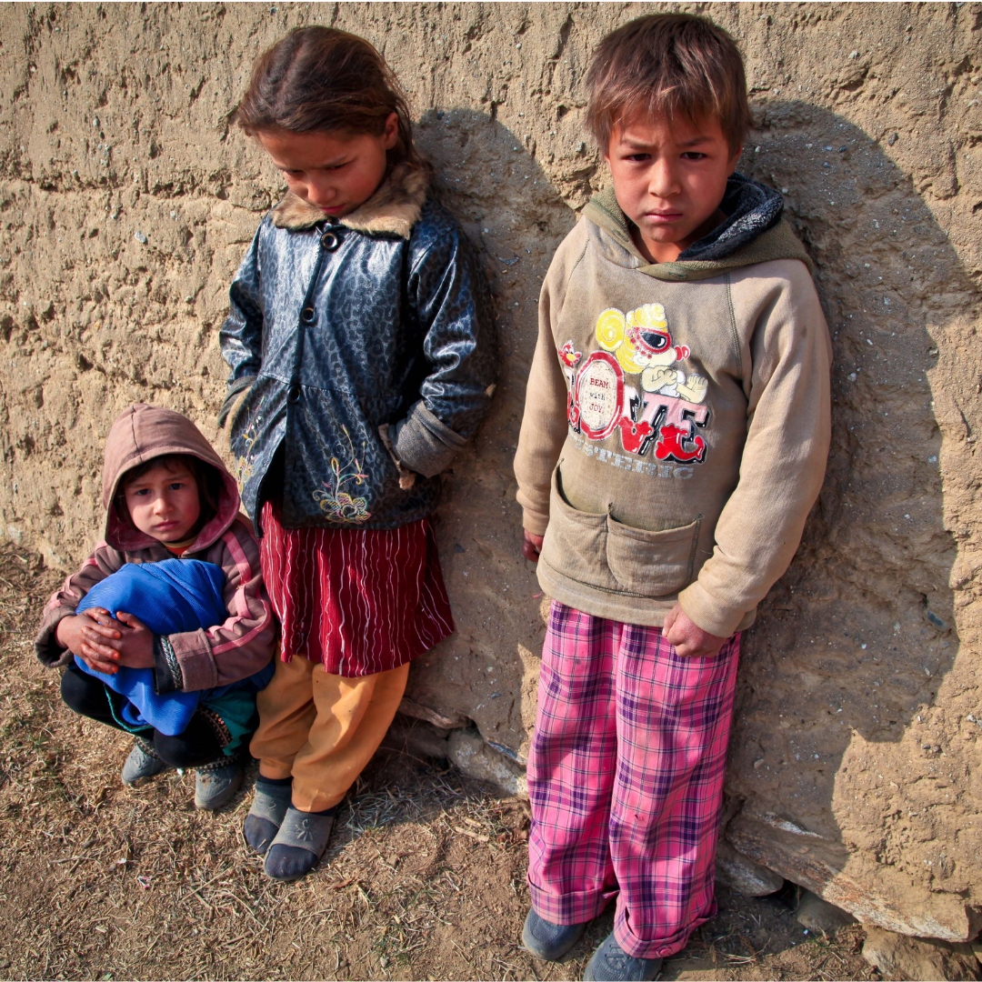 Three homeless kids standing outside in their pajamas