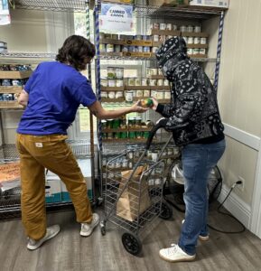 Volunteer handing a can to client in food pantry