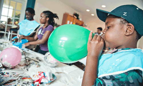 kid blowing up a balloon