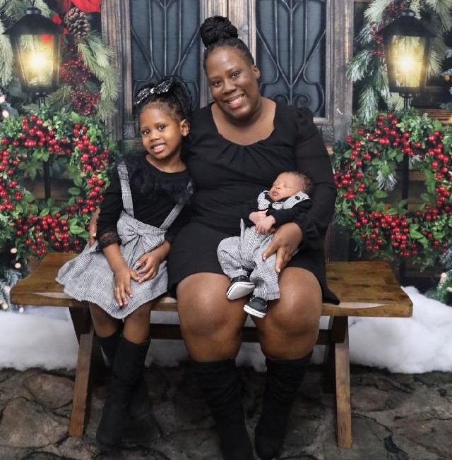 A mother sitting with her two children, smiling.